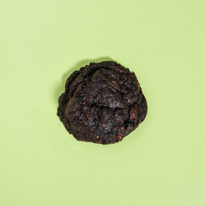 Vegan Raspberry Dark Choc New York Cookie by Crumbs & Doilies on green background, made with black cocoa and raspberries.